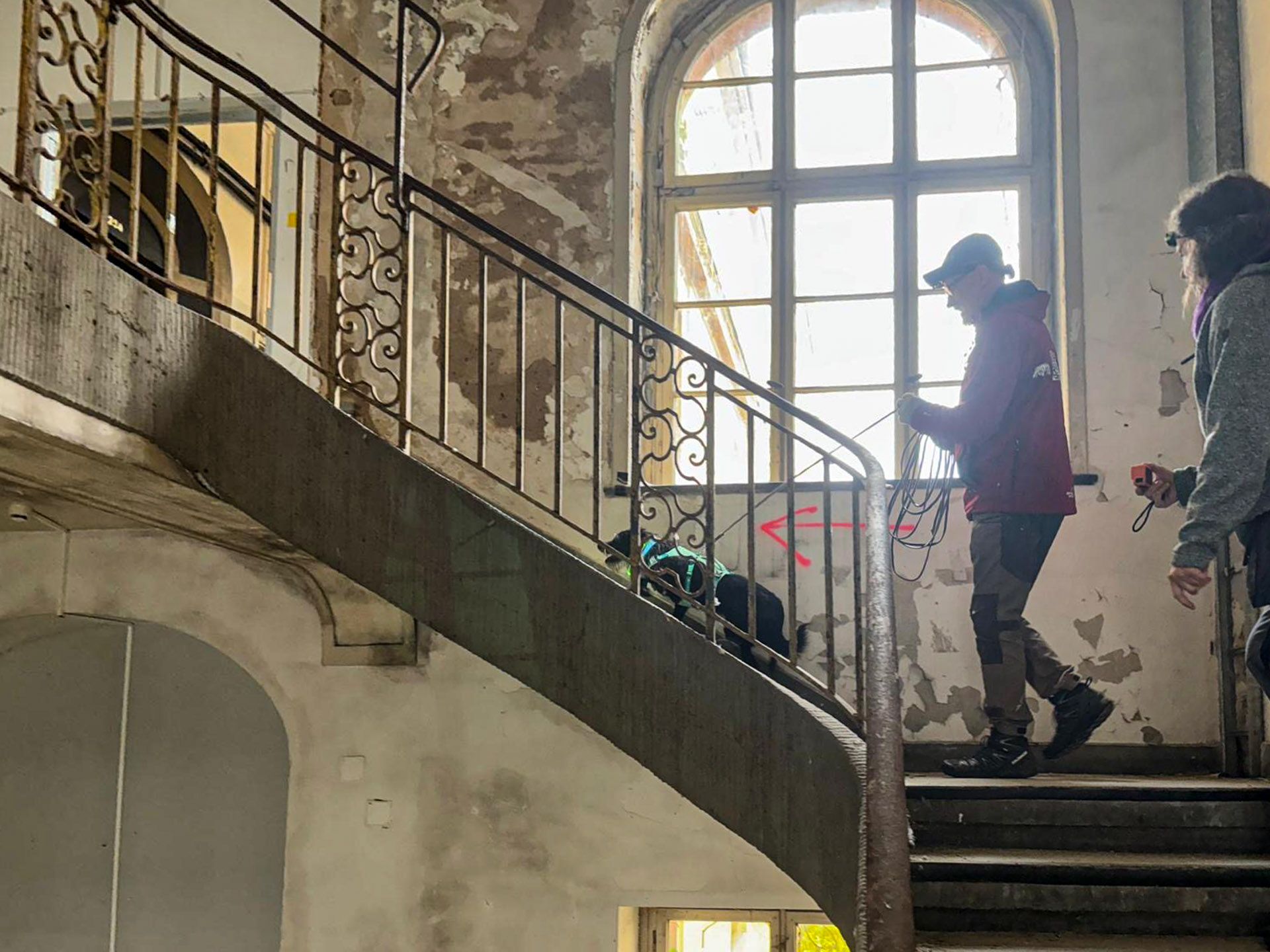 Sheena und ich in einem weiteren Treppenhaus, Graffiti und roter Pfeil an der Wand. Trainerin Tanja filmt mit der GoPro